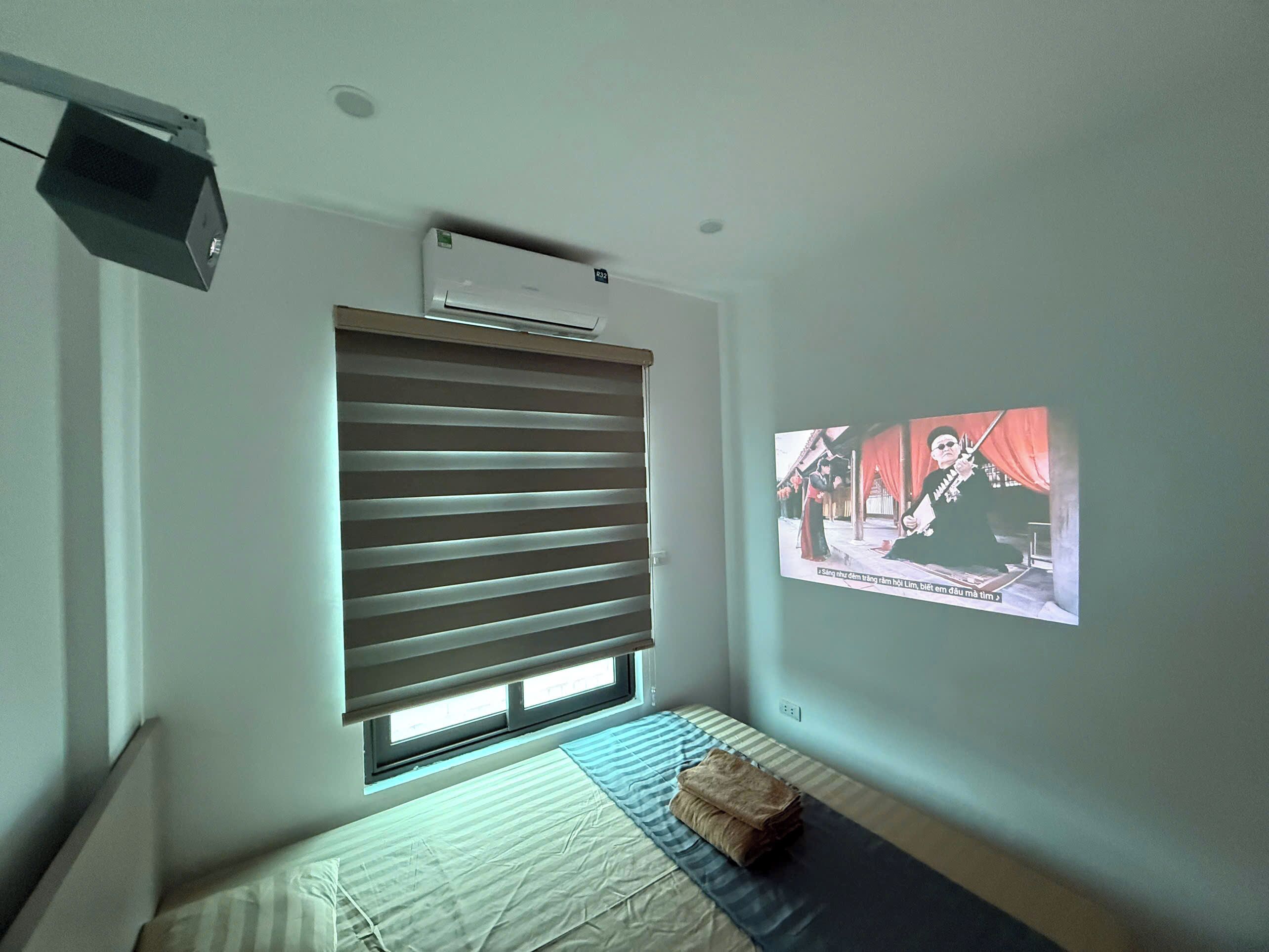 A bedroom with a bed, a projector screen, and an air conditioning unit.
