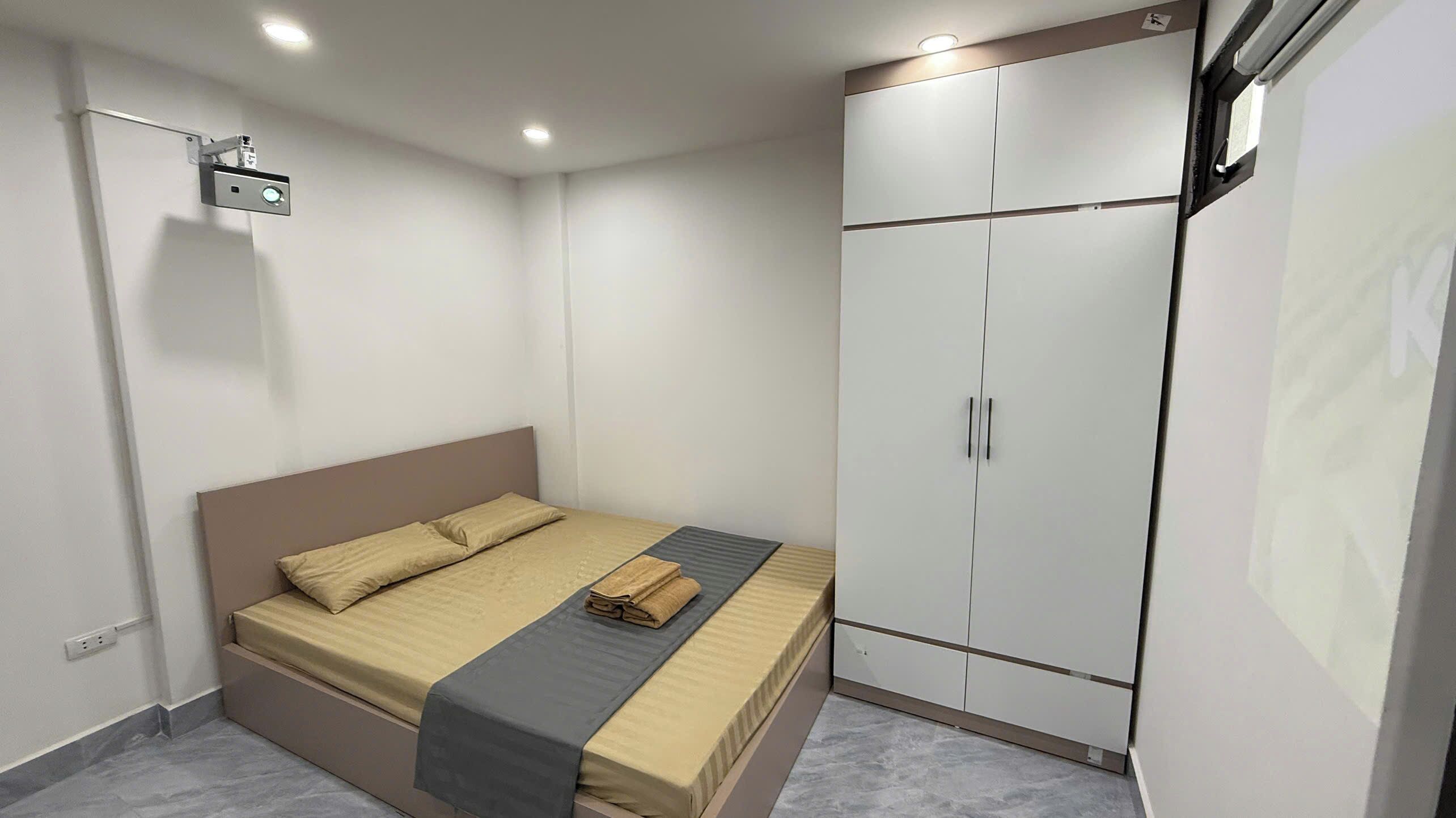Quarto com cama, guarda-roupa e projetor no teto.