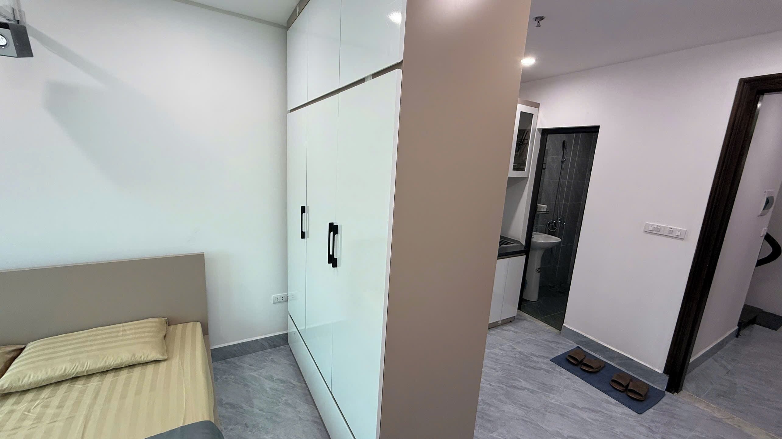 Un dormitorio moderno con cama, armario y un baño visible a través de una puerta abierta.