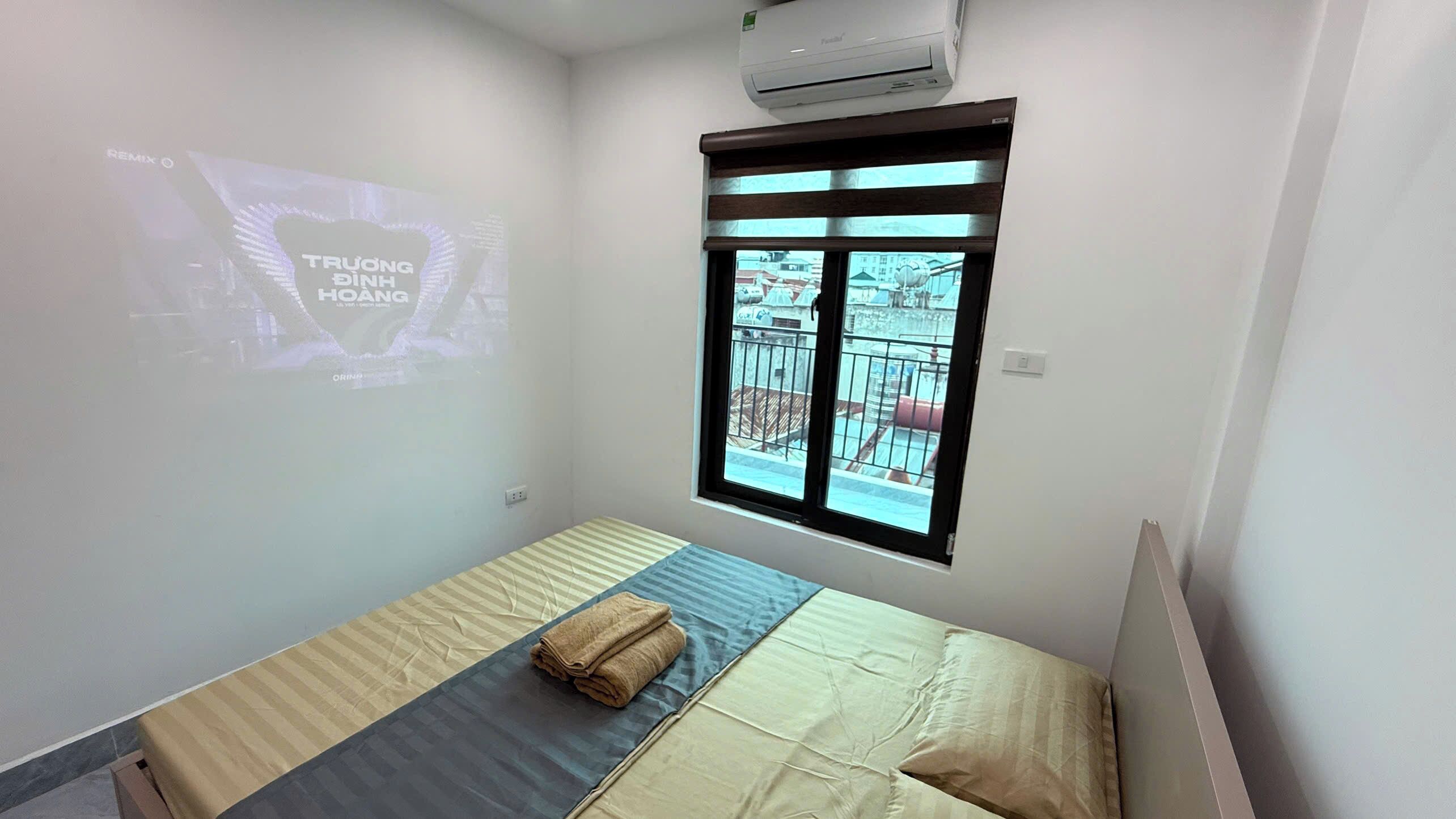 Une chambre à coucher avec un lit, une fenêtre et un écran de projection affichant une image.