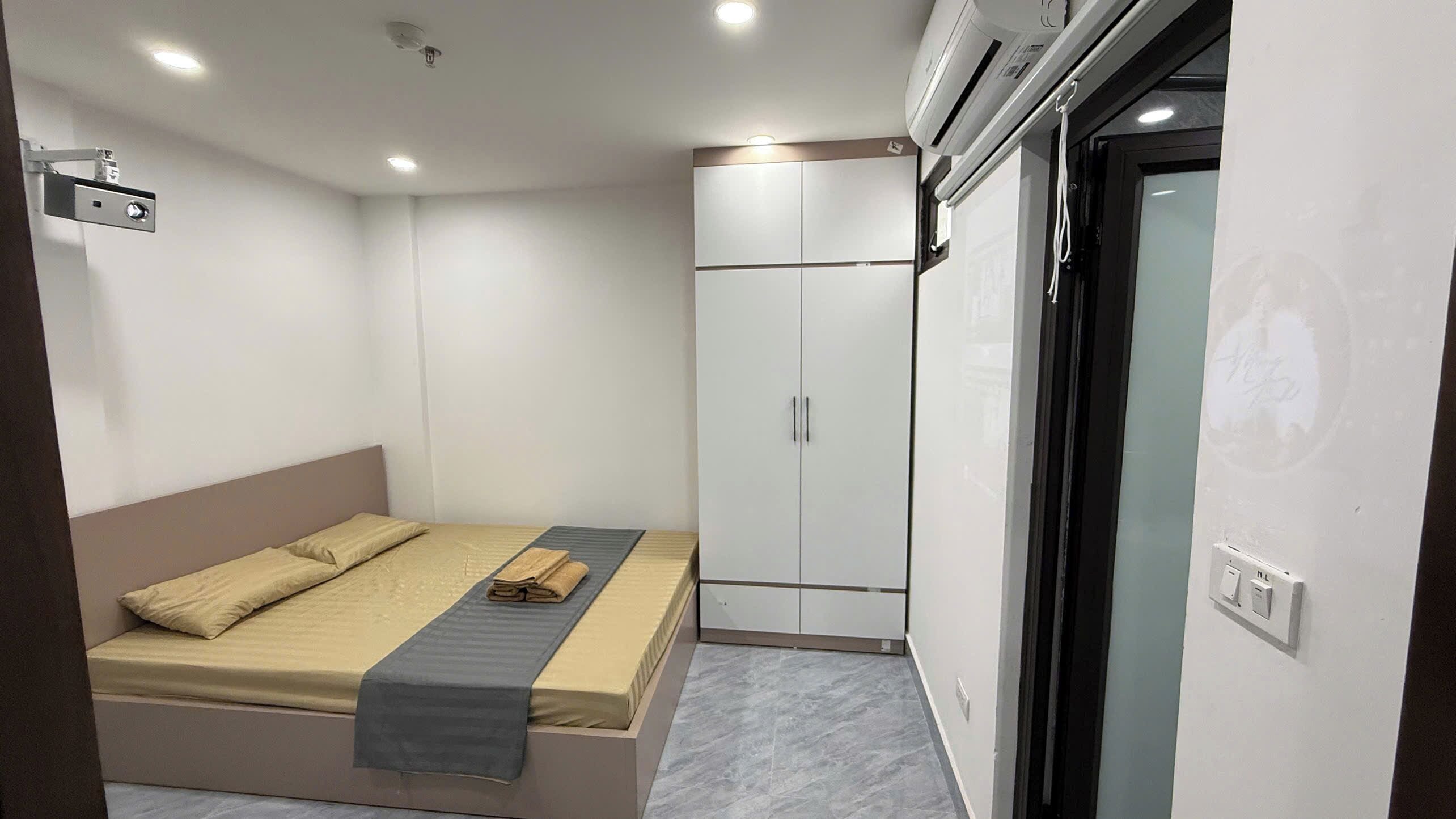 A compact bedroom with a bed, a wardrobe, and a built-in air conditioning unit.