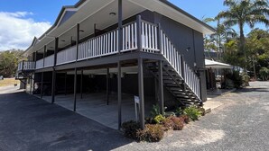 A two-story building with a covered outdoor area, a staircase, and a parking lot. - Agnes palms motel (Agnes Water)