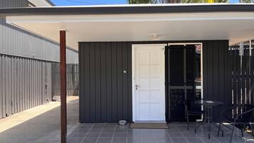 A covered patio with a door, a small table, and chairs.
