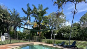 A rectangular swimming pool with clear water, surrounded by a black metal fence and palm trees. - Agnes palms motel (Agnes Water)