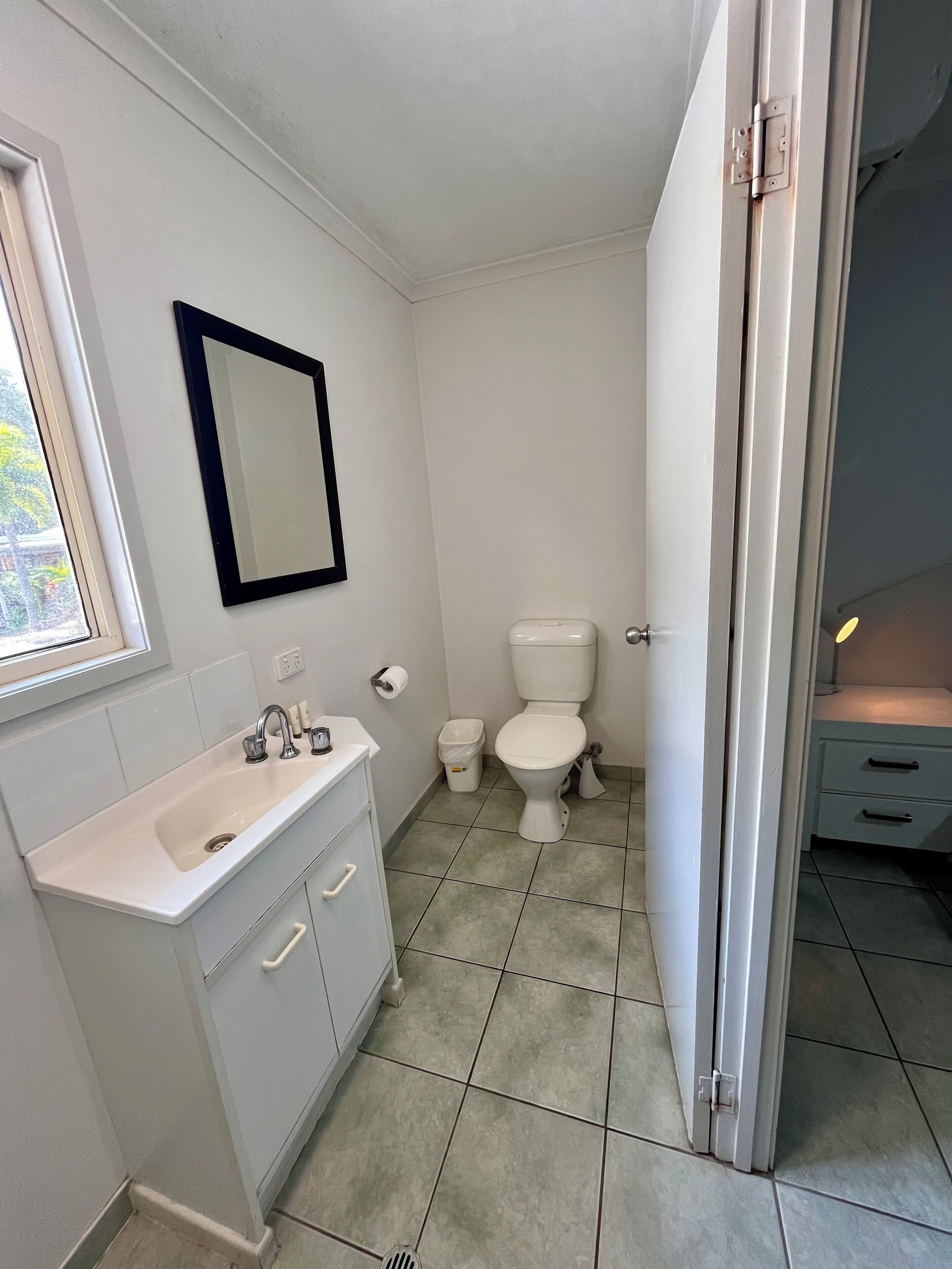 A small, clean bathroom with a white sink, mirror, and toilet.