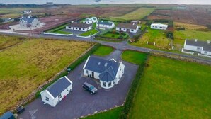 Vista aerea di una zona residenziale con case, un vialetto e un corpo d'acqua sullo sfondo.