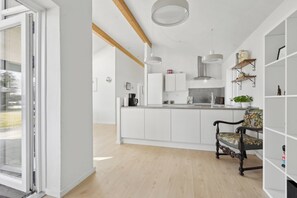 Eine moderne Küche mit weißen Schränken, Holzboden und einer Essecke mit einem gemusterten Stuhl.