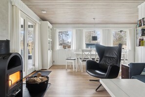 A cozy living room with a fireplace, a dining area, and a bookshelf.