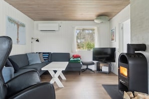 Ein Wohnzimmer mit Sofa, Fernseher, Kamin und einem Fenster mit Aussicht.