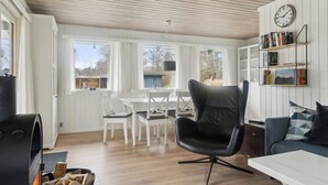 A cozy room with a fireplace, a dining area, and a bookshelf. - Lovely cottage in peaceful surroundings (Vejby)