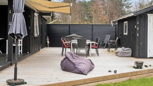 A deck with outdoor furniture, a covered area, and a building with a door.