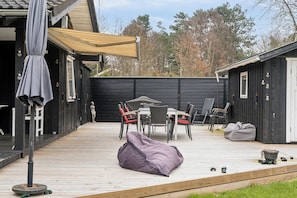Eine Terrasse mit Gartenmöbeln, einem überdachten Bereich und einem Gebäude mit einer Tür.