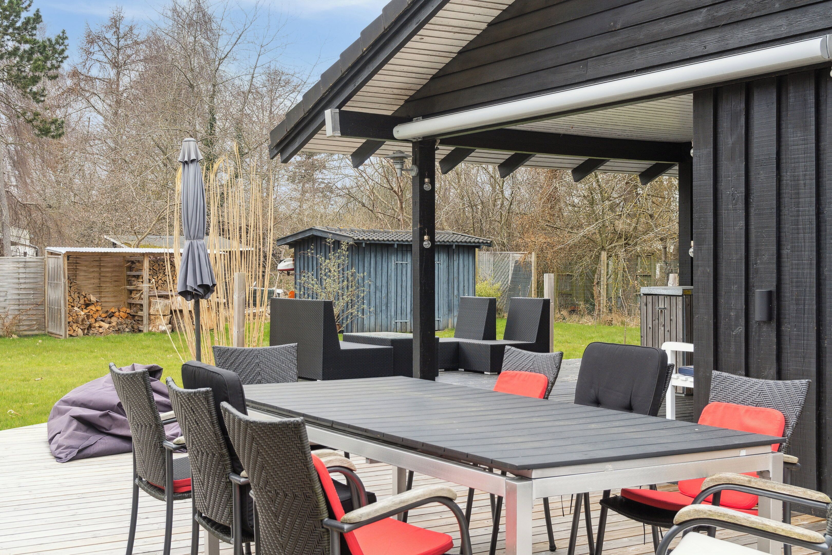An outdoor patio with a table and chairs, a covered seating area, and a wooden deck.
