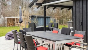 An outdoor patio with a table and chairs, a covered seating area, and a wooden deck. - Lovely cottage in peaceful surroundings (Vejby)