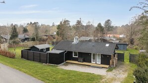 A modern building with a flat roof, a covered porch, and a number '16' on the side. - Lovely cottage in peaceful surroundings (Vejby)