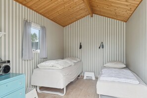 A room with two beds, a radio, a small stool, and a window with curtains.