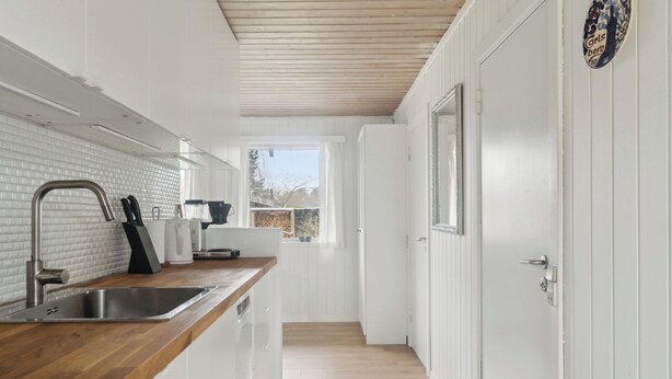 A modern kitchen with white cabinetry, a wooden countertop, and a stainless steel sink. - Lovely cottage in peaceful surroundings (Vejby)