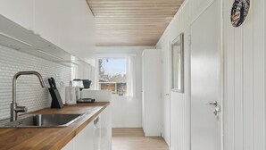 A modern kitchen with white cabinetry, a wooden countertop, and a stainless steel sink.