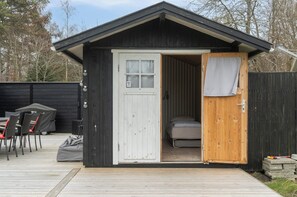 A small cabin with a wooden door, a window, and a bed inside.