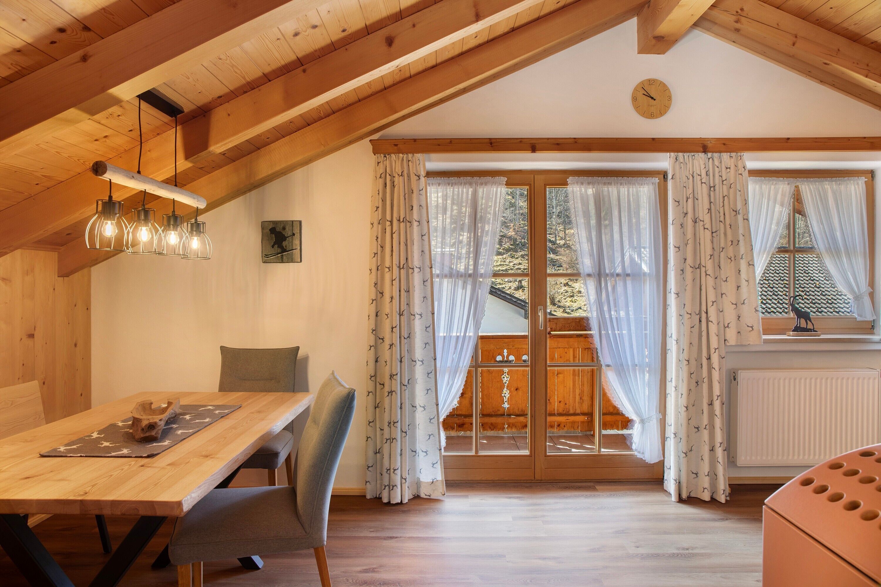 Ein Essbereich mit Holztisch, Stühlen und einer Pendelleuchte.