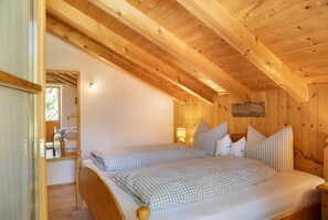 A wooden cabin bedroom with a bed, a nightstand, and a mirror.