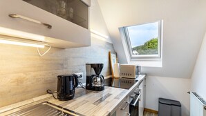 Une cuisine moderne équipée d’une machine à café, d’un grille-pain et d’une fenêtre donnant sur un espace verdoyant.