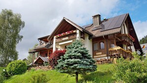 A traditional chalet with a balcony, a wooden staircase, and a sign indicating a guesthouse. - Room 'Lärche' with Mountain View and Wi-Fi (Bernau im Schwarzwald)