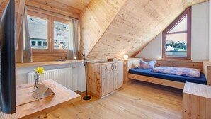 A wooden cabin with a loft bed, a desk with a lamp, and a radiator. - Room 'Lärche' with Mountain View and Wi-Fi (Bernau im Schwarzwald)