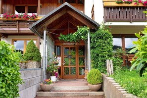 A wooden building with a balcony, a door with a heart-shaped decoration, and potted plants. - Room 'Lärche' with Mountain View and Wi-Fi (Bernau im Schwarzwald)