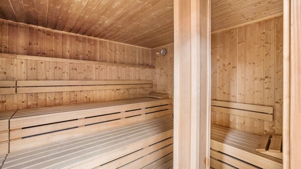Un sauna avec des bancs en bois et un plafond incliné.