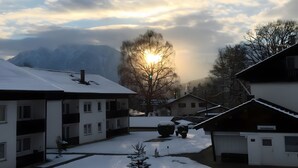 Un quartier résidentiel où le sol est recouvert de neige, avec un petit arbre et des bâtiments dont on peut voir les fenêtres et les balcons.
