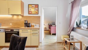 A modern kitchen with a dining area, a sofa, and a window with curtains. - Apartment 'Eulennestle' with Shared Terrace, Balcony and Wi-Fi (Lenzkirch)