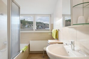 Un baño con ventana, un lavabo y un perchero para toallas.