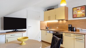 A compact kitchen with a dining area, a television, and a coffee maker. - Apartment 'Eulennestle' with Shared Terrace, Balcony and Wi-Fi (Lenzkirch)
