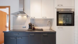 Eine moderne Küche mit Backofen, Edelstahl-Dunstabzugshaube und einer Kaffeemaschine.