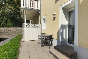Un patio con una mesa y sillas, una cerca blanca y un muro de piedra.