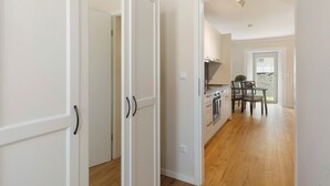 Une cuisine moderne avec un plancher en bois, des meubles blancs et un coin repas comprenant une table et des chaises.