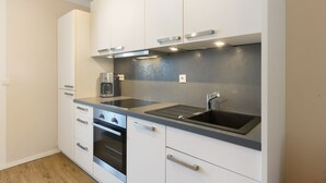 Una cocina moderna con armarios blancos, electrodomésticos de acero inoxidable y encimera gris.