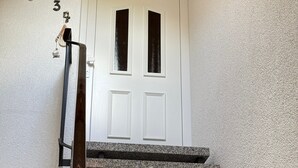 A white door with two windows, a wooden staircase, and a textured wall. - Apartment '4, Größe 60qm' with Balcony and Wi-Fi (Herscheid)