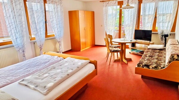 A hotel room with a bed, a desk with a chair, a television, and a sofa.