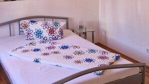 Ein Schlafzimmer mit einem Bett, einem Nachttisch, einer Wandlampe und einem Gemälde von Bambus und Blumen.