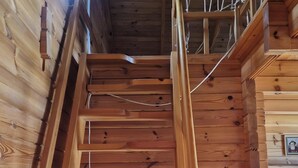 Un escalier en bois avec une rampe, des murs en bois et un plafond avec des poutres apparentes.