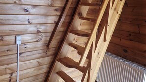 Un escalier en bois dans une pièce dotée d’un plafond en pente et d’un radiateur.