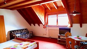 Una stanza con un letto, un divano, un tavolo da pranzo con sedie, una televisione e una finestra con tende.