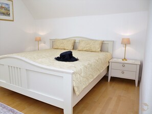 Un dormitorio con cama, mesitas de noche y una lámpara.