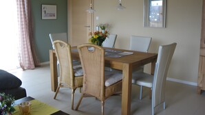 A dining area with a wooden table, wicker chairs, and a vase of flowers.