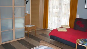A bedroom with a bed, a chair, a wardrobe, and a window with curtains.
