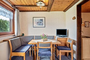 Puisesti sisustettu tila, jossa on penkkirivi, pöytä ja televisio.