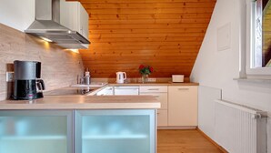 Una cocina moderna con techo de madera, estufa integrada y cafetera.