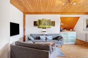 A modern living room with a grey sofa, a wooden coffee table, and a flat-screen TV.